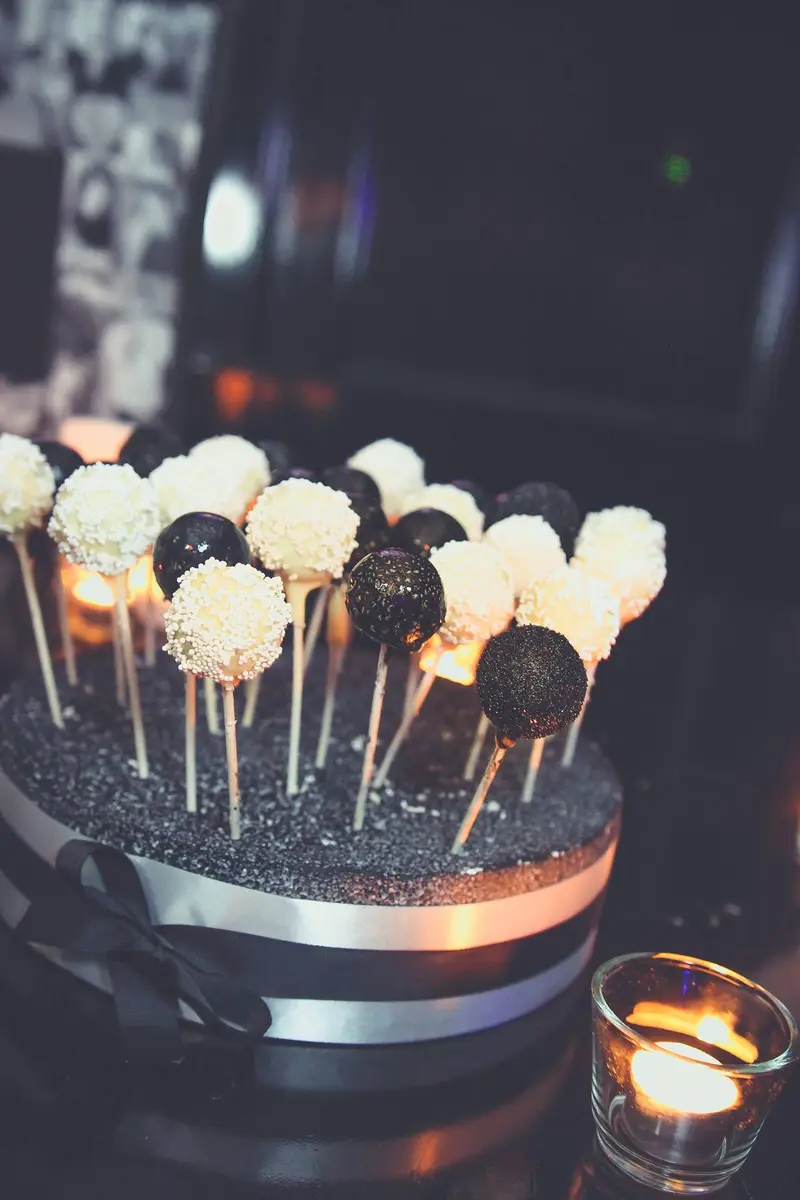 Black and white cake pops standing in a black glitter base, finished with a silver ribbon