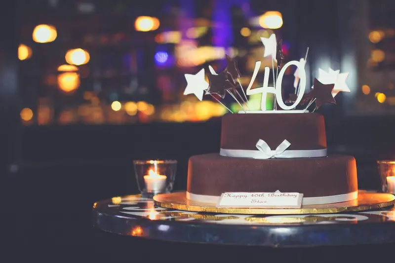 The same cake seen wide, ringed by tealights on a mirrored table
