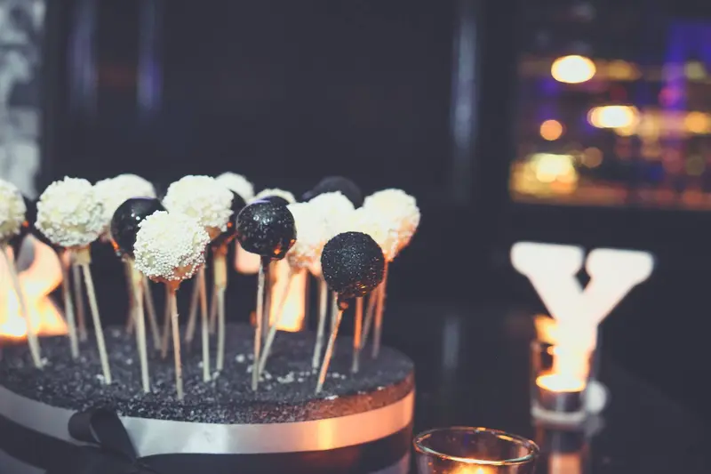 Cake pops in the foreground with an illuminated marquee letter glowing behind them