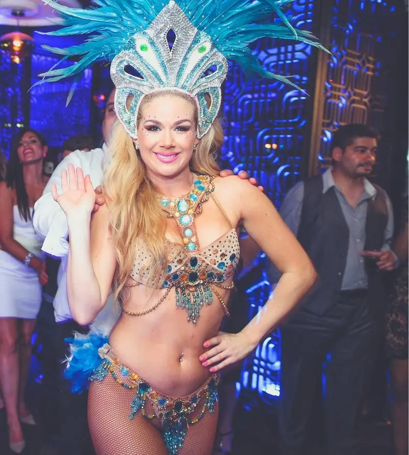 A carnival dancer in a turquoise feather headdress and jewelled costume on the dance floor