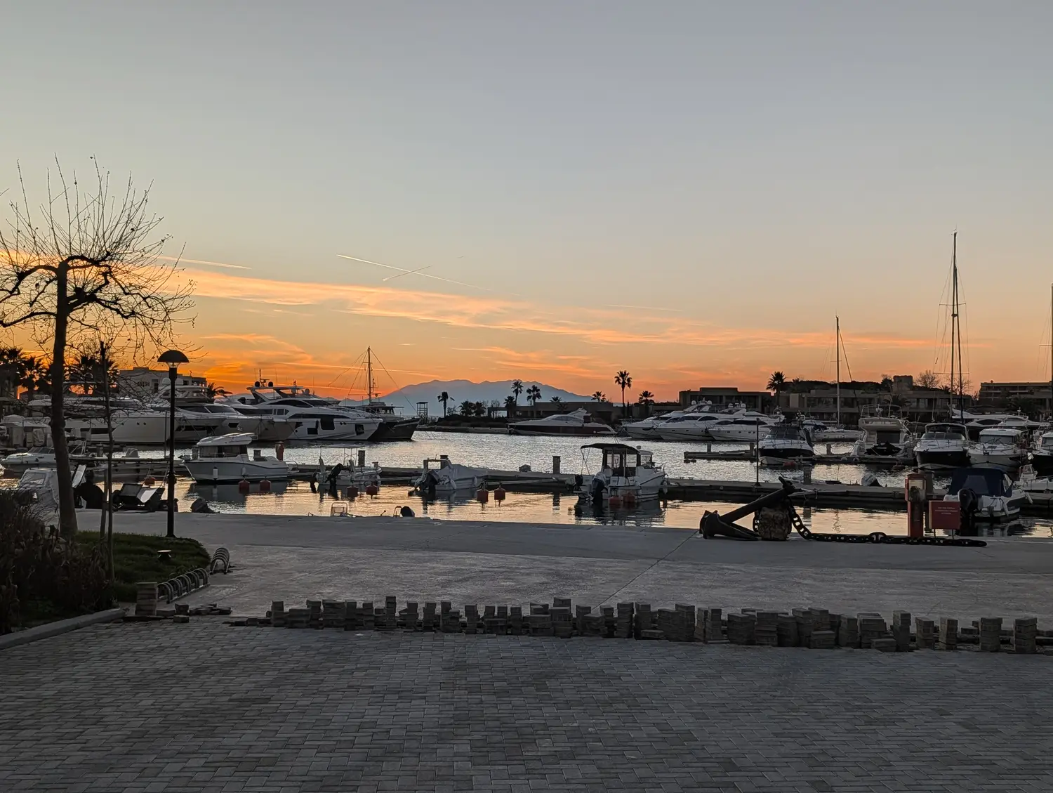 Yachts moored in a Halkidiki marina as the sun sets behind the mountains