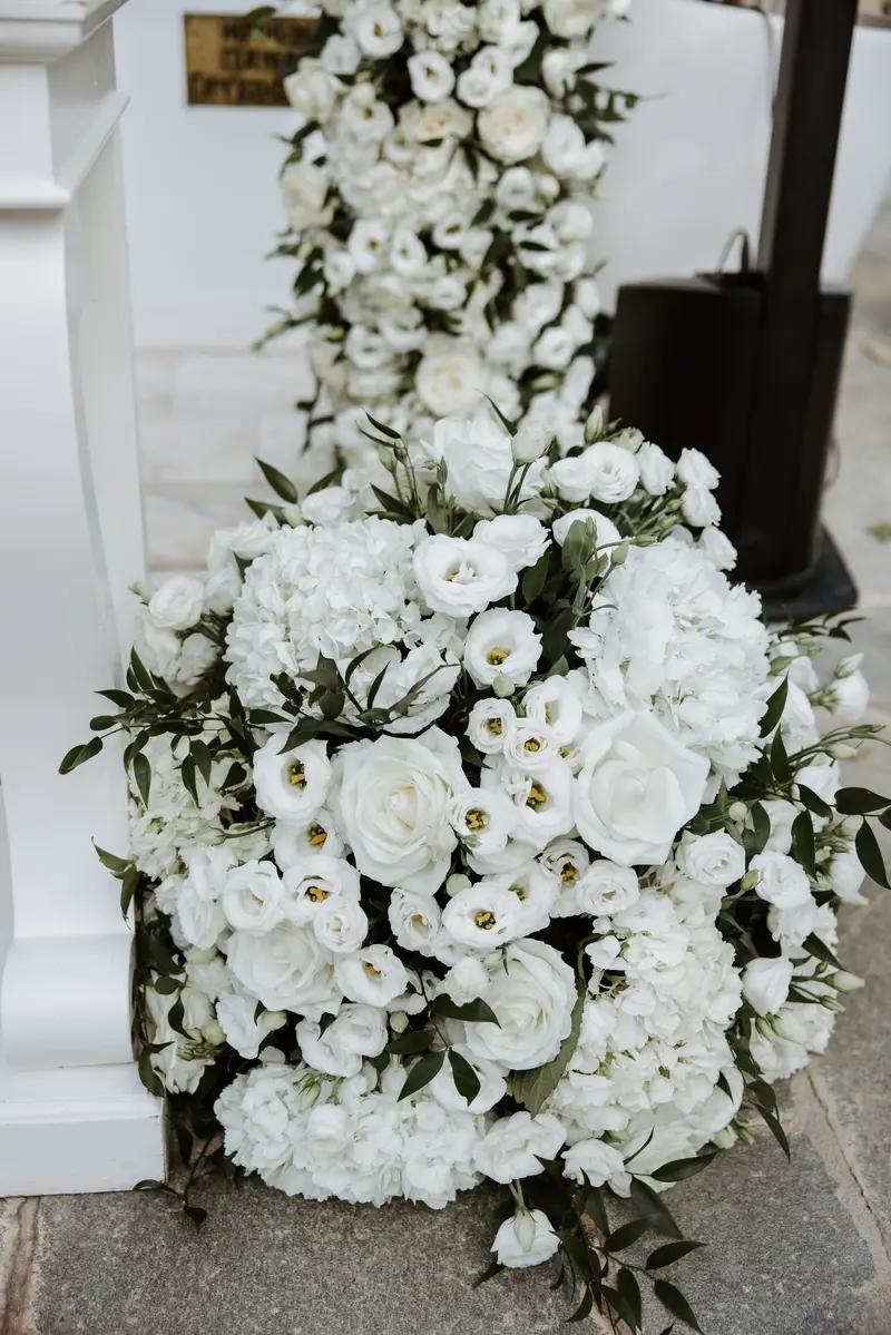 A dense arrangement of white roses and hydrangea banked against a column