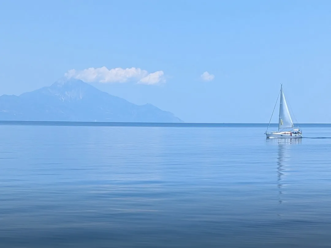 Still water off Halkidiki with Mount Athos on the horizon and a single white sailboat