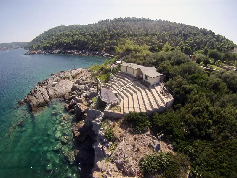 The whole wooded headland from further out, the amphitheatre on its point and pine running down to the water